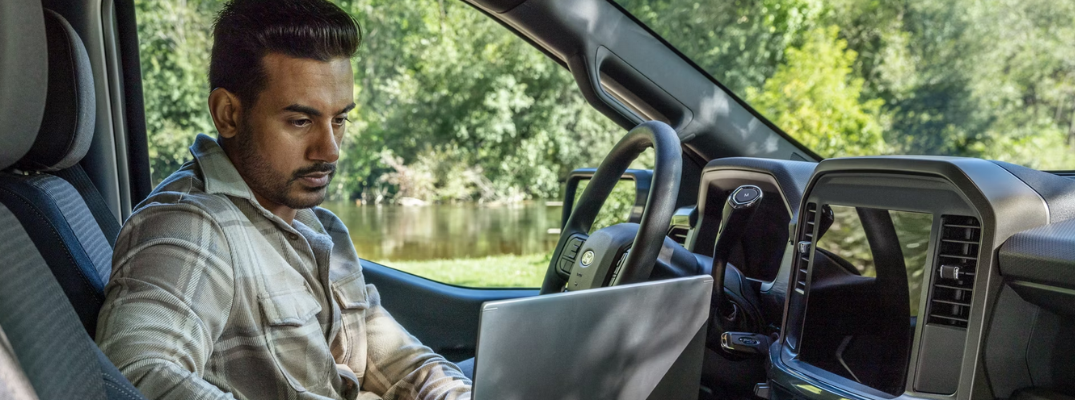 A man on his laptop inside his Ford truck